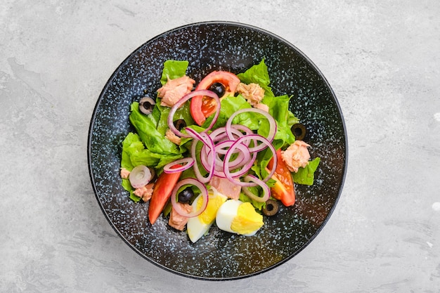 Draufsicht auf Salat mit Salat, Lachs, Tomate, gekochtem Ei und Zwiebel mit Oliven