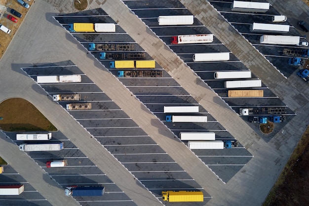 Draufsicht auf Sattelschlepper, die auf dem Parkplatz des Logistiklagers auf die Beladung warten Luftaufnahme von hoch