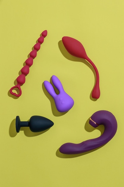 Draufsicht auf Sexspielzeug für Erwachsene wie Dildo-Vibrator-Buttplug auf gelbem Hintergrund Sexshop-Konzept