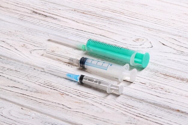 Draufsicht auf Spritzen unterschiedlicher Größe auf Holzhintergrund Medizinische Geräte für das Injektionskonzept mit Kopierraum
