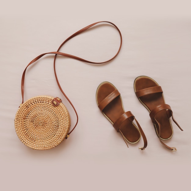 Draufsicht auf stylische Damensandalen und eine Korbtasche aus Rattan