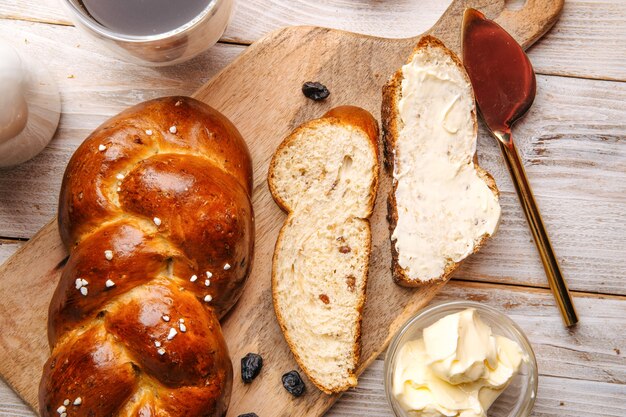 Draufsicht auf süßes Rosinenbrötchen-Zopfbrot auf dem verzierten hölzernen Hintergrund