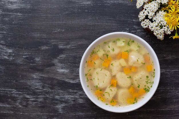 Draufsicht auf Suppe in Schüssel mit Knödeln auf schwarzem Hintergrund