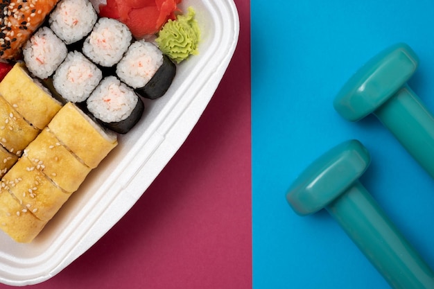 Draufsicht auf Sushi-Set auf farbigem Hintergrund Teller mit Rollen Ingwer und Vasabi