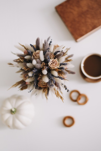 Draufsicht auf Tasse Kaffeebuch und getrocknete Blumen auf weißem Hintergrund