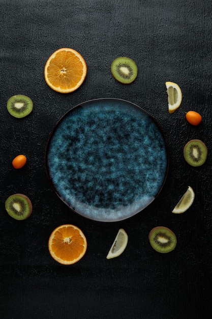 Draufsicht auf Teller mit orangefarbenen Kiwi-Zitronenscheiben mit ganzen Kumquats herum