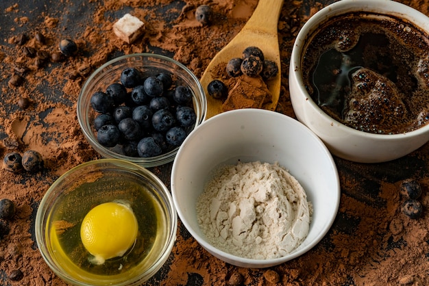 Draufsicht auf Zutaten zum Kochen oder Backen von Schokolade auf dem Tisch, Blaubeere, Ei, Mehl, Kakao und Pralinen