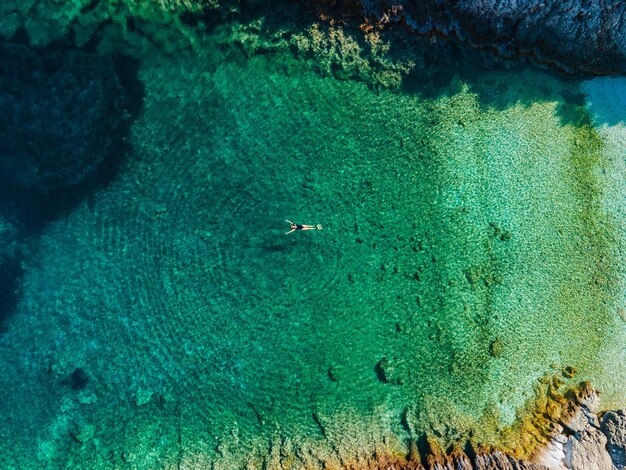 Draufsicht der Frau, die auf dem Rücken im klaren Meerwasser Griechenland-Urlaub schwimmt