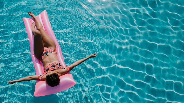 Draufsicht der Frau entspannend auf Matratze im Pool