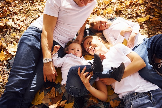 Foto draufsicht der fröhlichen jungen familie, die sich zusammen in einem herbstpark ausruhen.