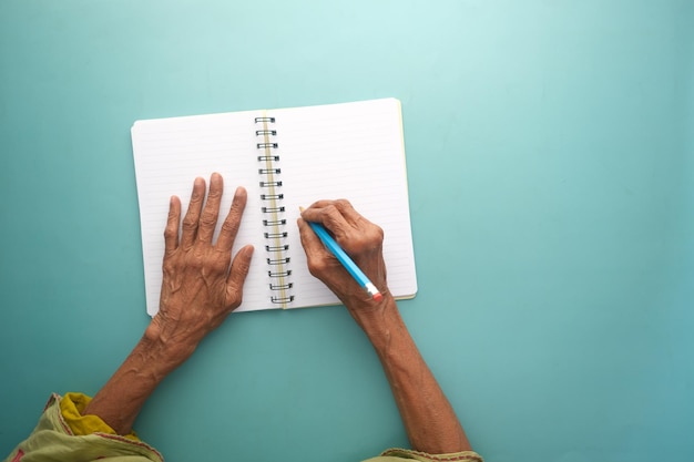 Draufsicht der Hand der älteren Frau auf leerem Papier auf dem Tisch