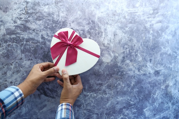 Draufsicht der Hand des Mannes, die eine Geschenkbox auf Tisch hält