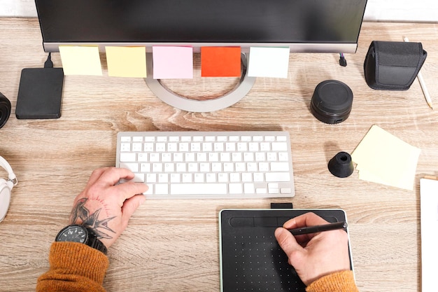 Draufsicht der Hand, die den Stift auf dem Grafiktablett für Retuschierarbeiten hält Ein Fotograf verwendet eine Bearbeitungsanwendung, um Bilder in einem Fotostudio zu retuschieren