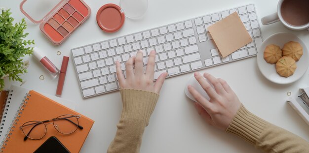 Draufsicht der jungen Frau schreibend auf Tastatur im warmen beige weiblichen Arbeitsplatzkonzept