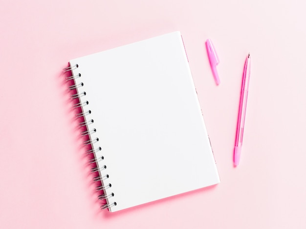 Draufsicht der leeren Notiz mit Stift auf rosa Hintergrund
