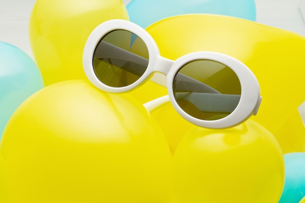 Draufsicht der modischen Sonnenbrille gemacht mit den gelben und blauen Ballonen