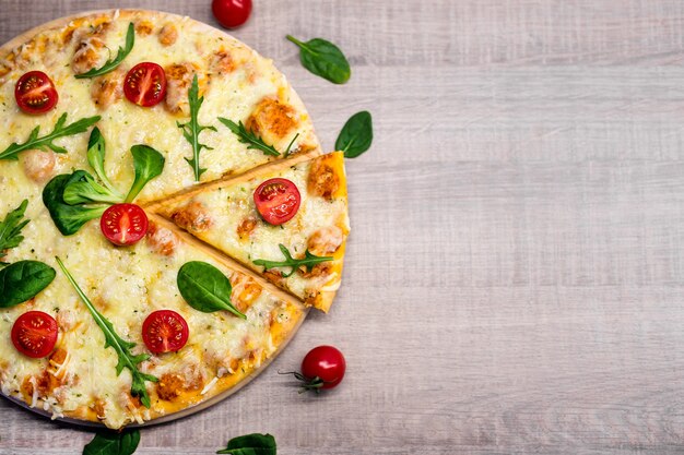 Draufsicht der Pizza mit Tomaten und Kräutern über Holztisch