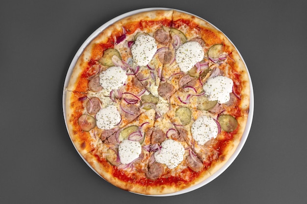 Draufsicht der Pizza mit Wurst, in Essig eingelegter Gurke, Zwiebel und Meerrettich