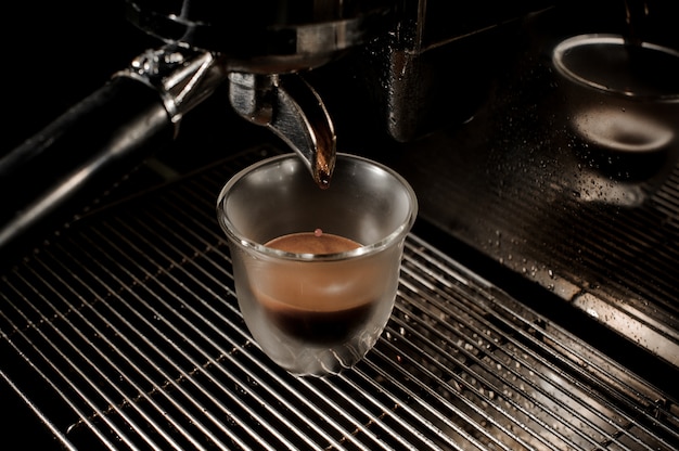 Draufsicht der professionellen modernen Kaffeemaschine, die einen frischen und aromatischen Kaffee in eine Schale gießt