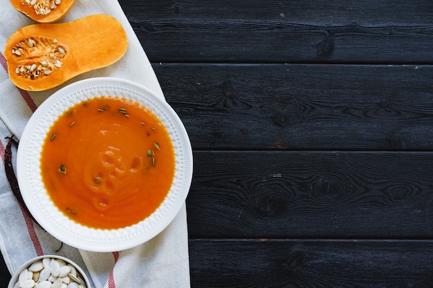 Draufsicht der pürierten Kürbissuppe in einer weißen Schüssel auf dunklem Tisch