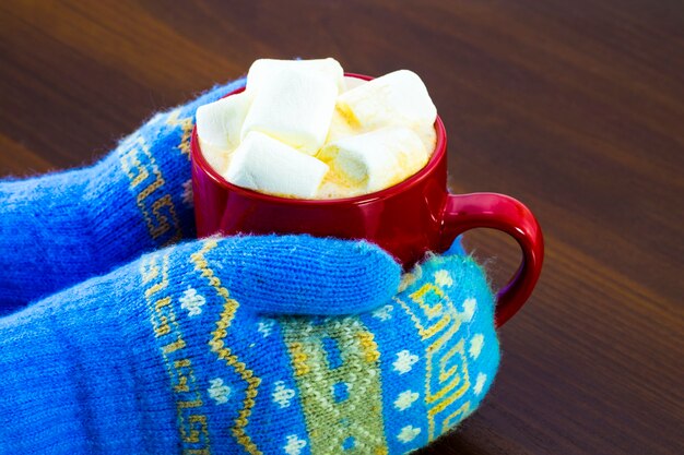 Draufsicht der roten Tasse der heißen Schokolade und der Marshmallows in der weiblichen Hand