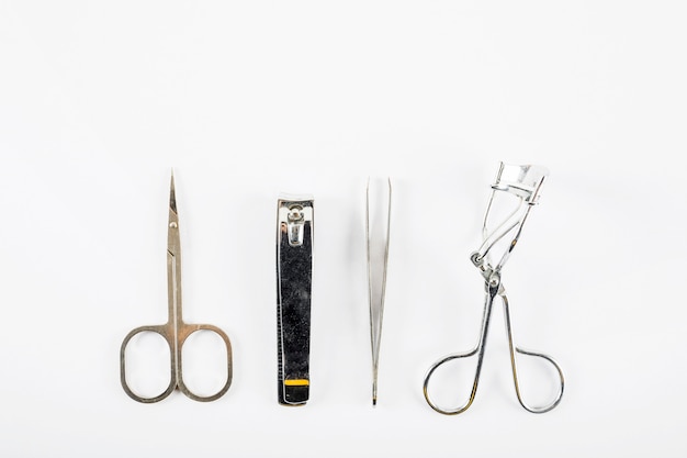 Foto draufsicht der schere; nagelknipser; pinzette und wimperlockenwickler auf weißem hintergrund