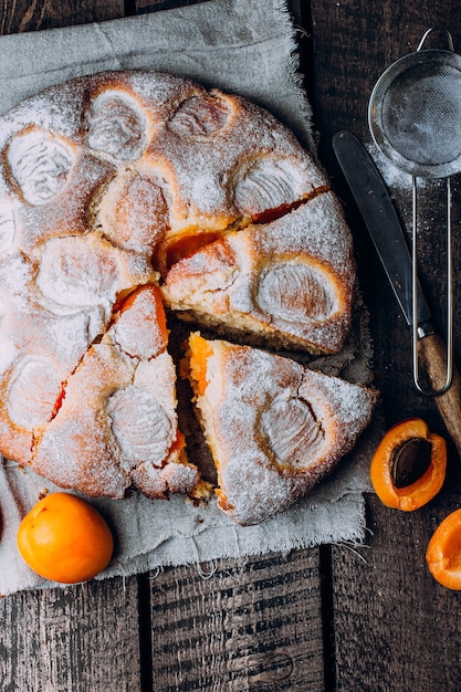 Draufsicht der selbst gemachten Aprikosentorte auf Serviettenholztischhintergrund. Sommer Obstkuchen