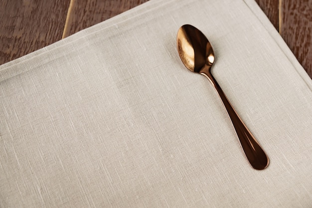 Draufsicht der Stoffserviette der beige Farbe und des gedienten Teelöffels auf Holztisch.