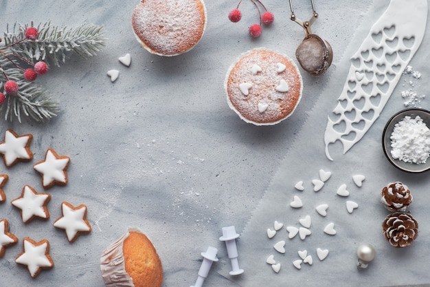 Draufsicht der Tabelle mit Zucker-besprühten Muffins, Fondantzuckerglasur und Weihnachtssternplätzchen auf hellblauem