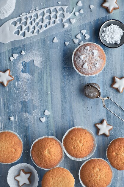 Draufsicht der Tabelle mit Zucker besprühten Muffins, Fondantzuckerglasur und Weihnachtssternplätzchen auf Purpleheart