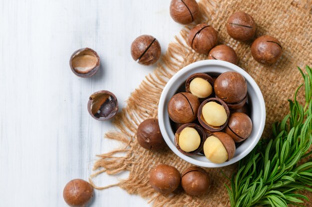 Draufsicht der trockenen gerösteten Macadamia-Nuss in der weißen Tasse auf Holzhintergrund,