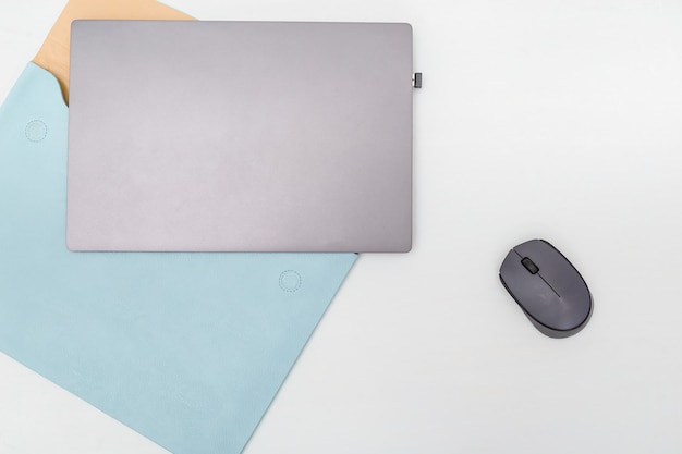 Draufsicht der weißen Arbeitstabelle mit modernem Laptop, blauem Ledertasche und drahtloser Maus. Arbeitsraum