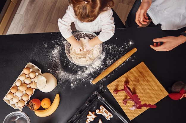 Foto draufsicht des bruders mit seiner kleinen schwester, die essen in der küche zubereiten und spaß haben.