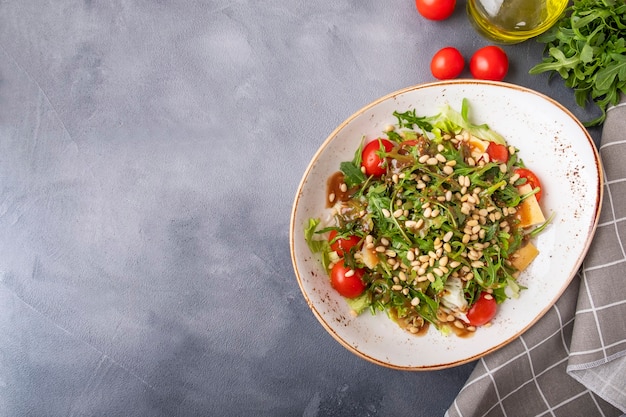 Draufsicht des Diät-Rucola-Salats mit frischen Tomaten, Käse und Pinienkernen. Textraum