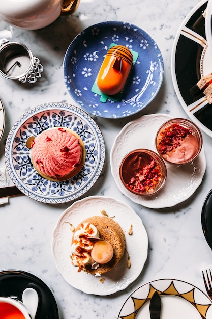 Draufsicht des englischen Nachmittagsteesets mit heißem Tee, Gebäck, Scones, Mousse und Besteck.