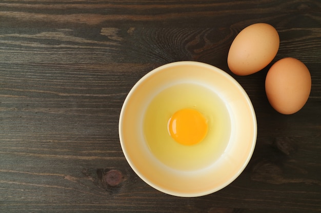 Draufsicht des frischen rohen Eies in einer Schüssel auf Holztisch