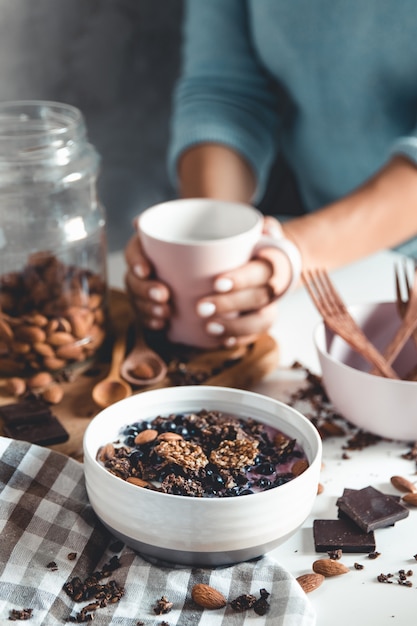 Draufsicht des Frühstückstisches mit Kaffee, Müsli, Nüssen, Beeren und Milch