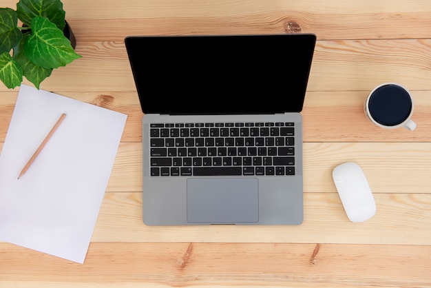 Foto draufsicht des hölzernen schreibtisch-tisches mit laptop, papierblock, bleistift und kaffeetasse