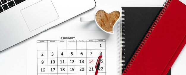 Foto draufsicht des kalenders der februar-seite mit stift auf, notizblöcken, tasse kaffee und laptop. vorlage, bürokonzept