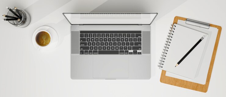Foto draufsicht des laptops mit leerem bildschirm kaffeetasse zwischenablage und kopienraum auf weißem modernen tisch