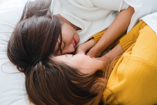 Draufsicht des lesbischen glücklichen Paars der schönen jungen asiatischen Frauen, das beim zusammen liegen umarmt und lächelt