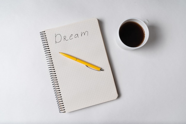 Draufsicht des Notizblocks mit der Aufschrift Traum. Stift und Tasse Kaffee. Motivationsnotiz