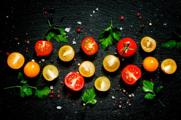 Draufsicht des roten gelben und orange Kirschtomaten des Lebensmittelhintergrundes schwarzer Hintergrund