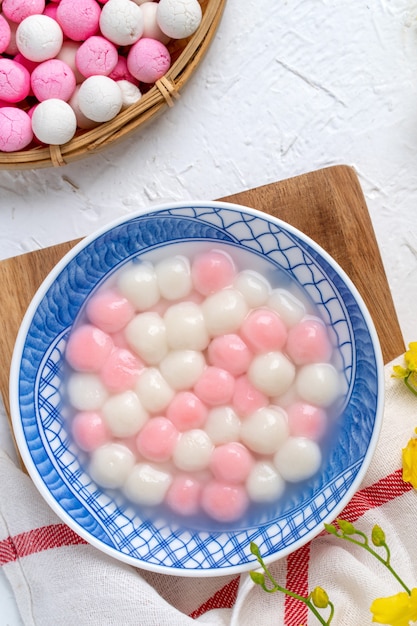 Draufsicht des roten und weißen Tangyuan (Tang Yuan, Klebreisknödelbällchen) in der blauen Schüssel auf weißem Hintergrund für Wintersonnenwende-Festessen.