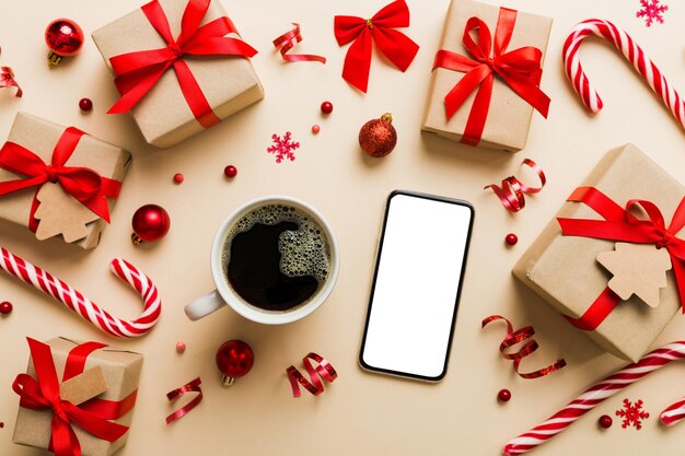 Draufsicht des Smartphones mit heißer Tasse Kaffee Weihnachtsdekoration auf farbigem Hintergrund