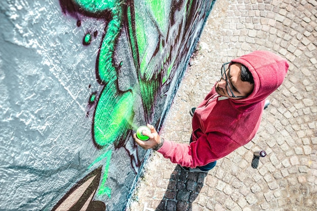 Draufsicht des Straßenkünstlers, der Graffiti auf generischer Wand malt