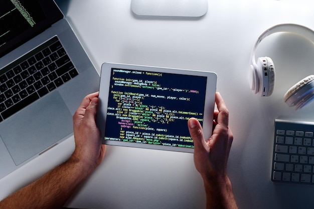 Draufsicht des Tablet-Bildschirms mit codierten Daten, die von einem männlichen Programmierer gehalten werden