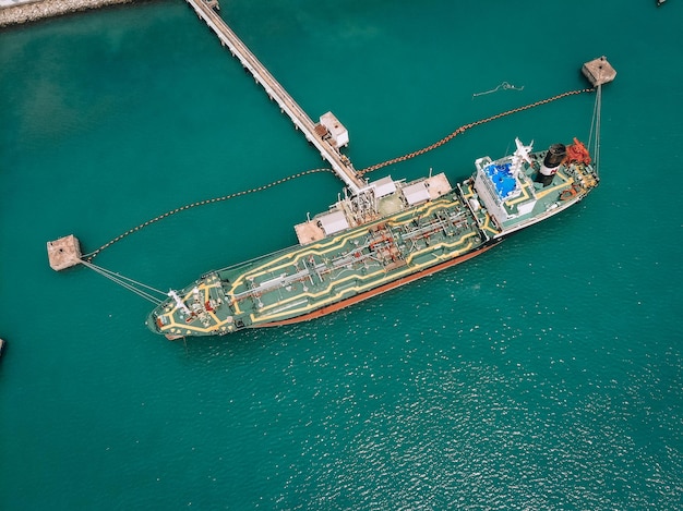 Draufsicht des Tankers, der Kraftstoff durch die Ölleitung zum Depotterminal an der Küste pumpt; industrielles Konzept.