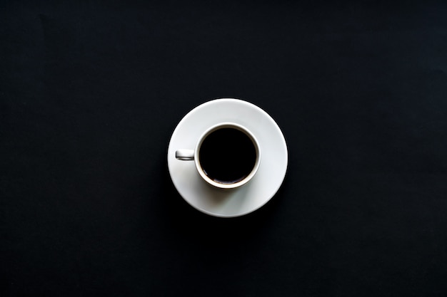 Draufsicht des weißen Tasse Kaffees auf schwarzem Hintergrund. Minimale Flachlage.