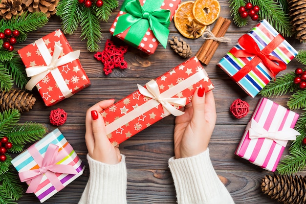 Draufsicht eine Frau, die eine Geschenkbox in ihren Händen auf festlichem hölzernem hält. Tanne und Weihnachtsschmuck. Zeit